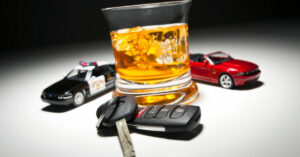 A glass of liquor with a set of car keys