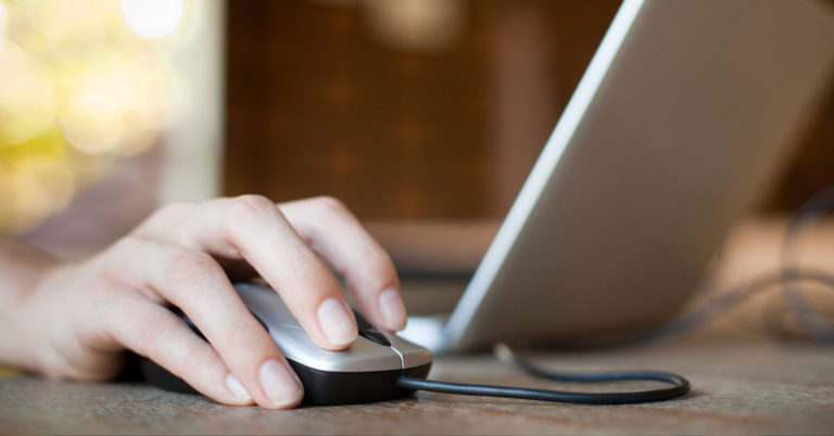 Mujer haciendo clic en el mouse frente a la computadora portátil