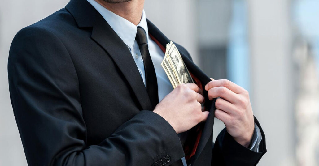 Businessman hiding cash in his suit pocket