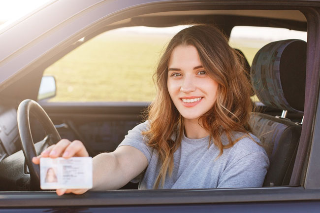 Woman smiling and presenting her driver's license
