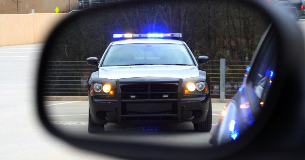 Police car with its lights on in a rearview mirror