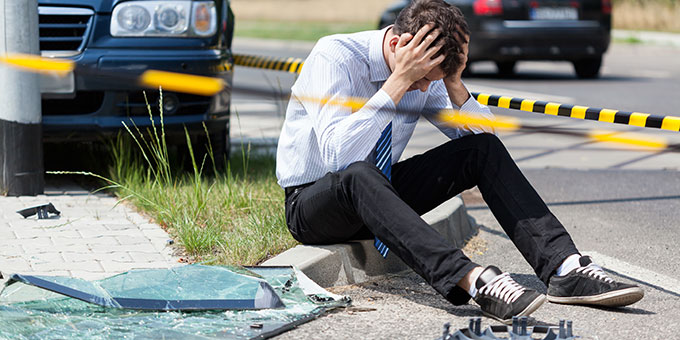 Vehicular Manslaughter lawyer tampa - Man sitting on side or road holding his head after accident